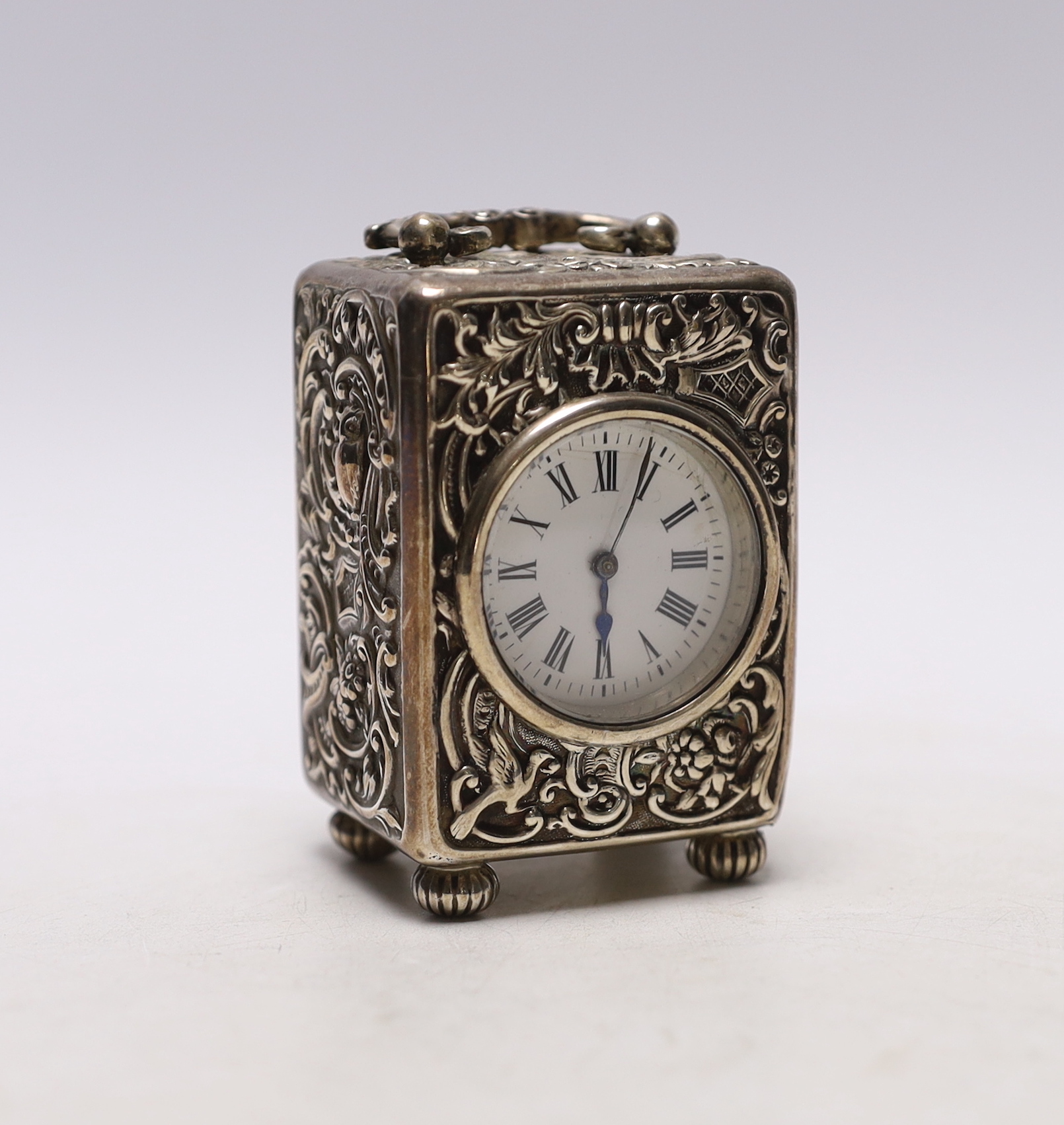 A late Victorian repousse silver cased carriage timepiece, by William Comyns, London, 1899, with Roman dial and key, height 8cm.